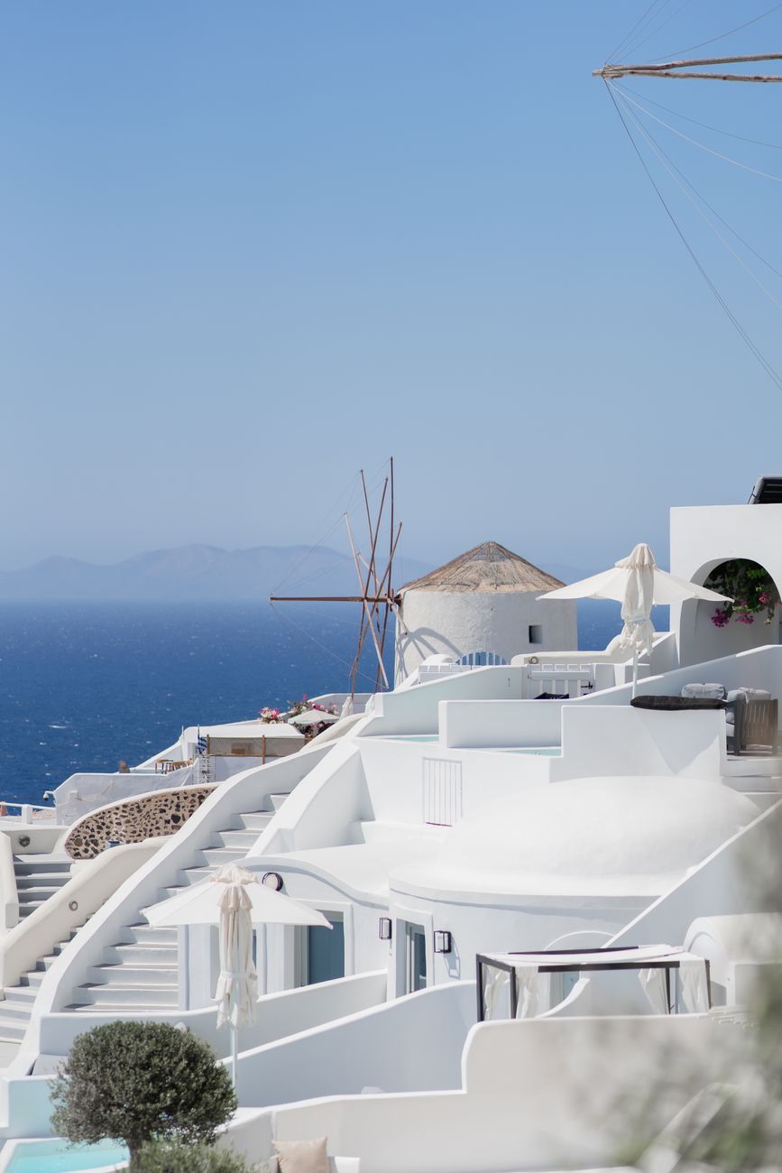 a white building with a blue roof and a blue ocean in the background
